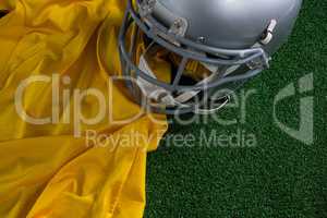 American football head gear and jersey lying on artificial turf