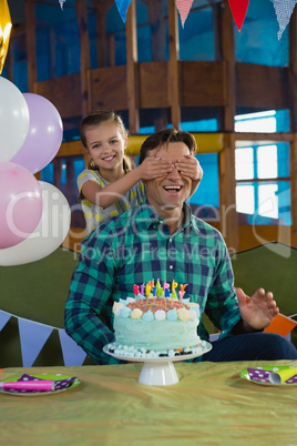 Girl closing her fathers eyes during birthday party