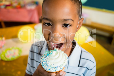 Portrait of cute boy having cupcake during birthday party