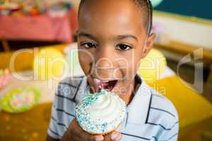 Portrait of cute boy having cupcake during birthday party