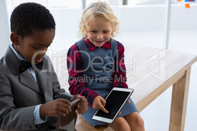 Business people using tablet computers while sitting on wooden table