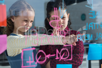 Female colleagues anlayzing data at seen through glass