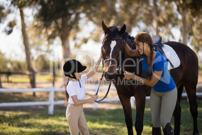 Happy girl and female jockey stroking horse