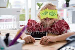 Playful businesswoman with adhesive notes on eyes at office