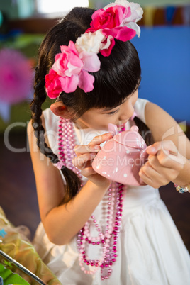 Close-up of cute girl holding toy teapot during birthday party