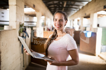 Portrait of smiling female jockey holding laptop