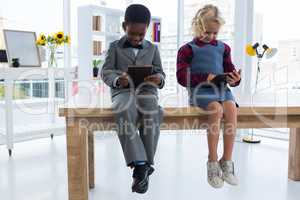 Business people using digital tablets while sitting on table in creative office
