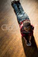 Boy lying on wooden floor using mobile phone