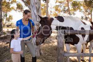 Woman assisting girl for cleaning horse