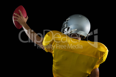 American football player holding a ball high in one hand