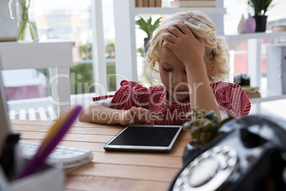 Businesswoman using tablet while sitting at table in office