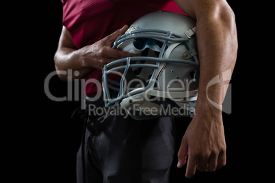 American football player holding a head gear under his arms