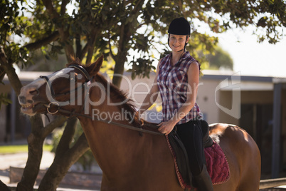 Portrait of happy female jockey sitting on horse