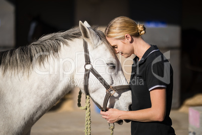 female jockey loving horse at barn