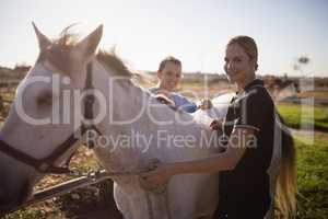 Portrait of female jockey and vet standing by horse