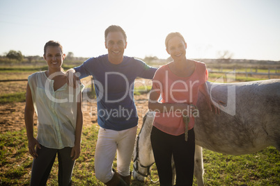 Portrait of male trainer with young women standing by horse
