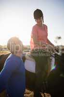Trainer looking at young woman riding horse