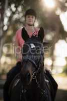 Female jockey riding horse at barn