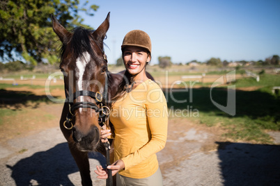 Confident female jockey with horse standing on field