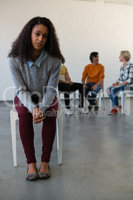 Portrait of woman sitting on chair with friends in background