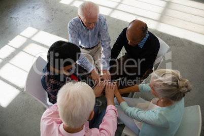 High angle view of senior friends stacking hands