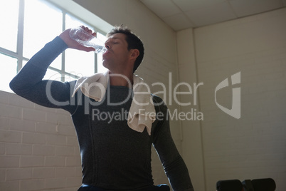 Athlete drinking water while standing in gym