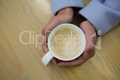 Cropped hands of woman holding coffee cup at cafe