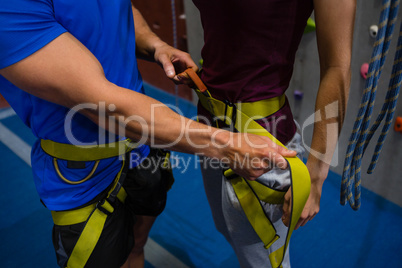 Midsection of trainer adjusting female athlete harness