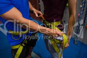 Midsection of trainer adjusting female athlete harness