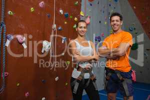 Portrait of confident athletes standing by climbing wall in gym