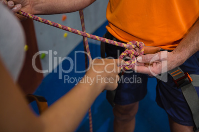 Hand of woman typing harness of man in gym