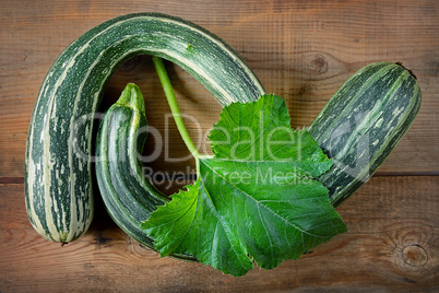 green zucchini courgettes in brown wooden background
