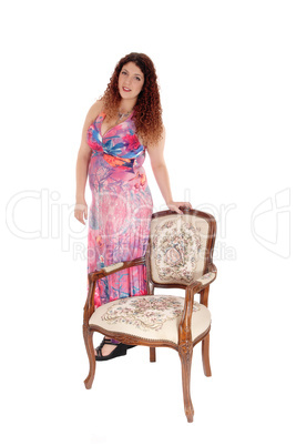 Lovely young woman standing with armchair