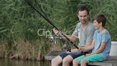 Positive father and son fishing together on pond