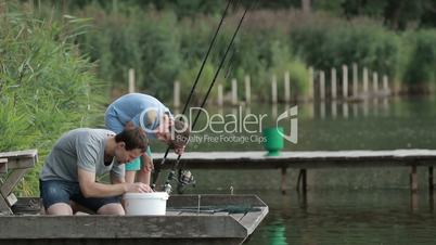 Fisherman baiting hook on fishing rod at lake