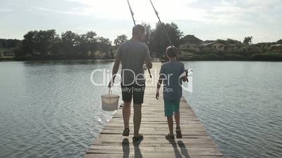 Father and son going fishing with rods on lake