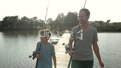 Happy dad and son with rods going fishing on pond