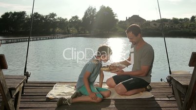 Handsome boy enjoying aroma of fried fish on lake