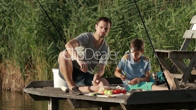 Family enjoying meal by the lake while fishing