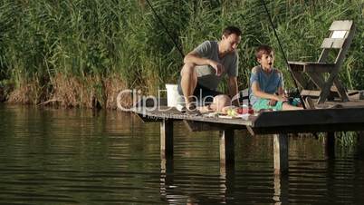 Fishermen having breakfast on wooden pier at pond