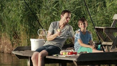 Hipster father and son enjoying picnic by the pond