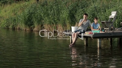 Father and son enjoying fishing together on lake