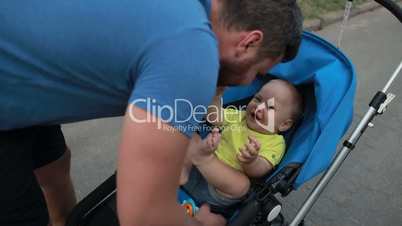 Loving father playing with toddler son in stroller