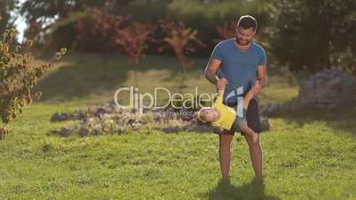Positive dad playing with toddler son in nature
