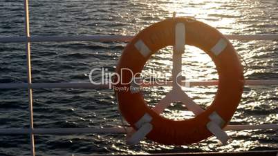 Red lifebuoy on a boat crossing the sea at sunset