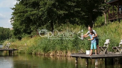 Father teaching son to fish at freshwater pond