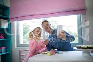 Girl and father taking a selfie while playing with a toy kitchen set