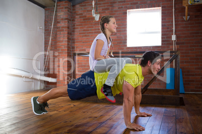 Trainer and teenage girl exercising in gym