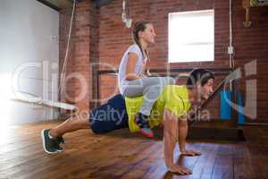 Trainer and teenage girl exercising in gym
