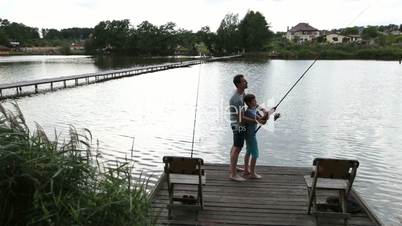 Father and son angling at tranquil lake in summer